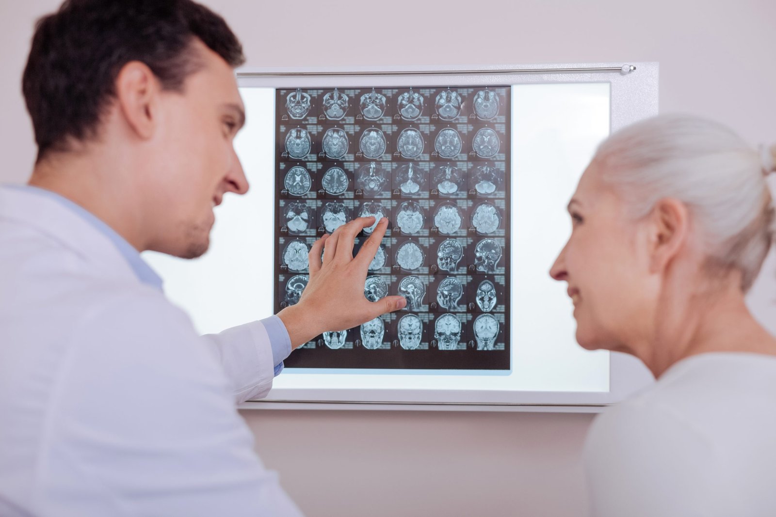 delighted positive handsome doctor looking his patient smiling while telling her good news scaled